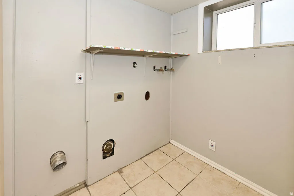 Utility room featuring tile flooring, a mounted shelf, and a window