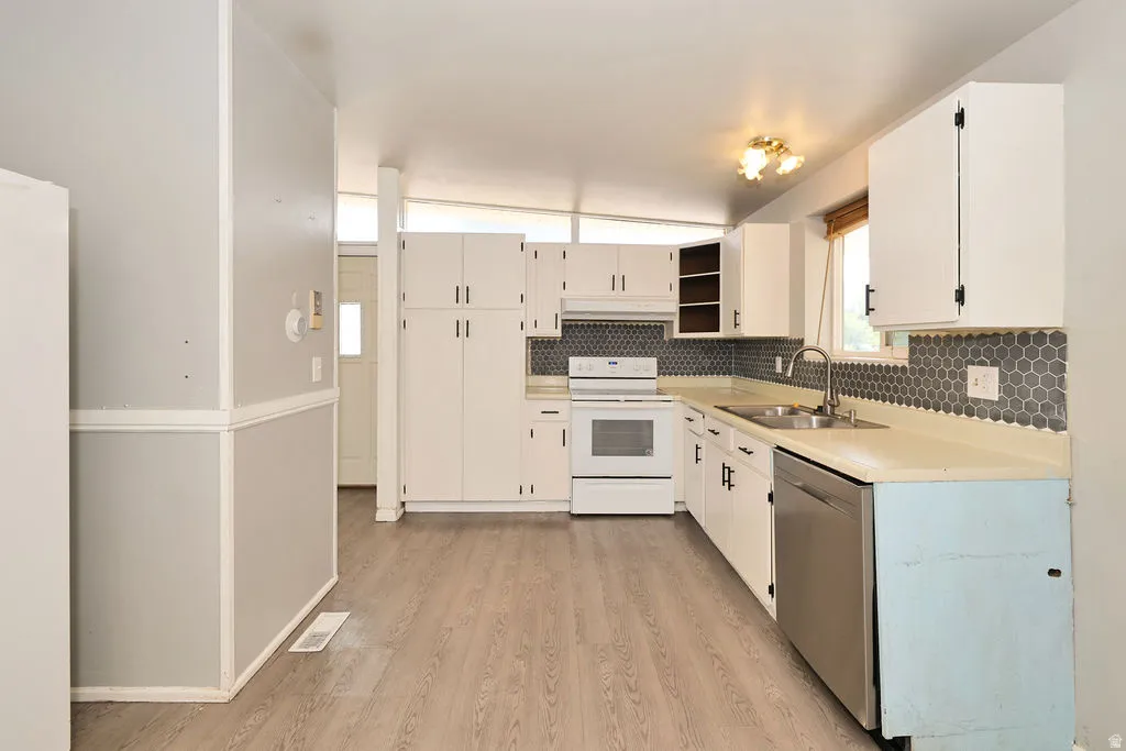 Kitchen featuring wood-finish flooring, white cabinetry, a hexagonal tile backsplash, a stainless steel sink, and a stainless steel dishwasher