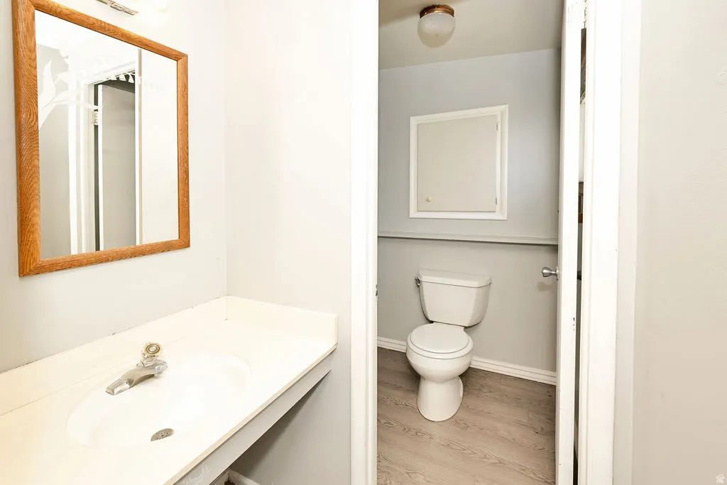 Vanity with an integrated sink and chrome faucet, rectangular mirror with a wood-finish frame, and overhead lighting