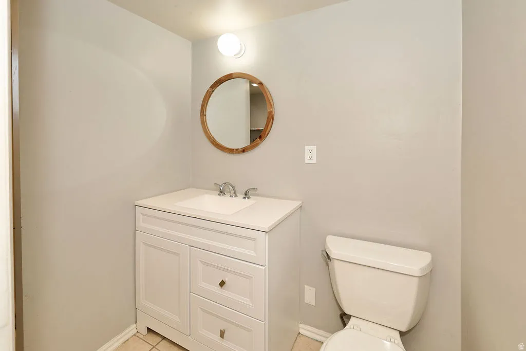 White vanity with a single basin sink, chrome faucet, and round wood-frame mirror