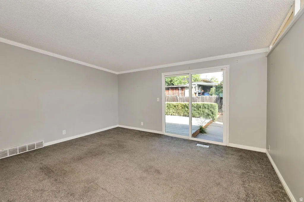 Sliding glass door to outdoor space, light gray walls, and textured ceiling