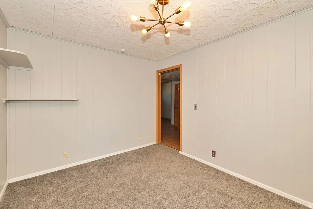 Textured ceiling with a modern light fixture, paneling on walls, and carpet flooring