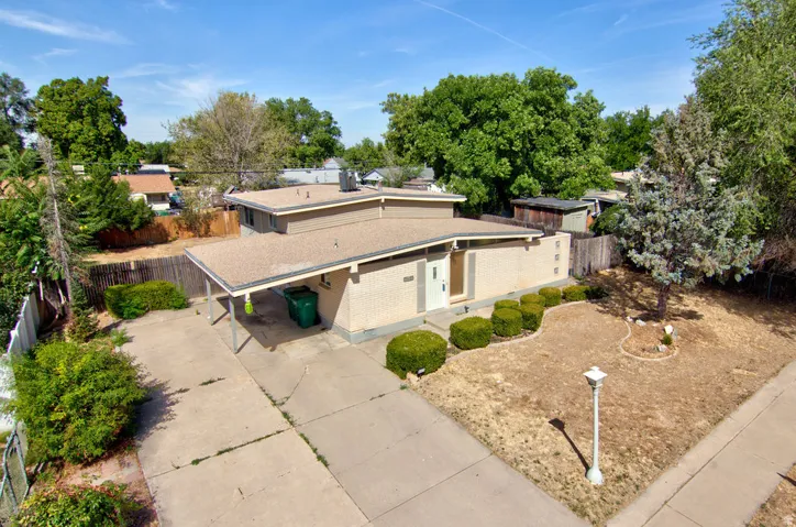 Brick exterior with a covered carport, concrete driveway, and front yard landscaping