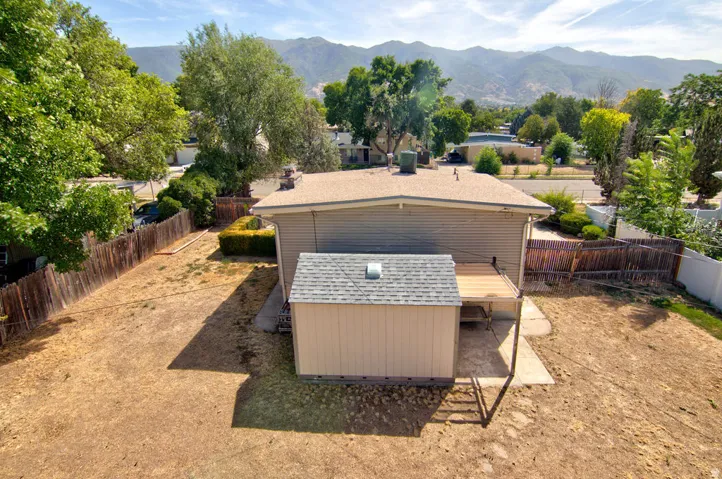 Expansive backyard with a wood privacy fence, mature trees, a storage shed, and a wood deck
