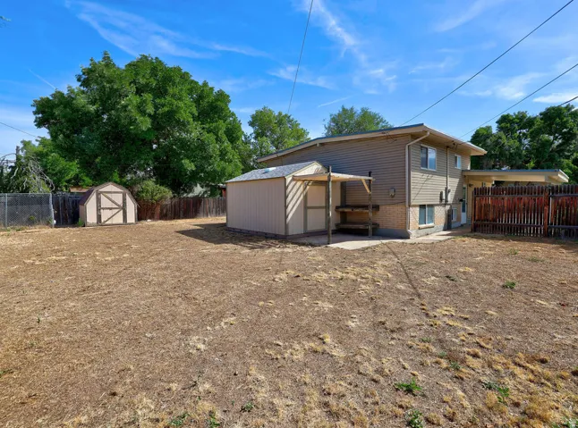 Expansive backyard featuring a large shed, a smaller shed, and a covered patio area