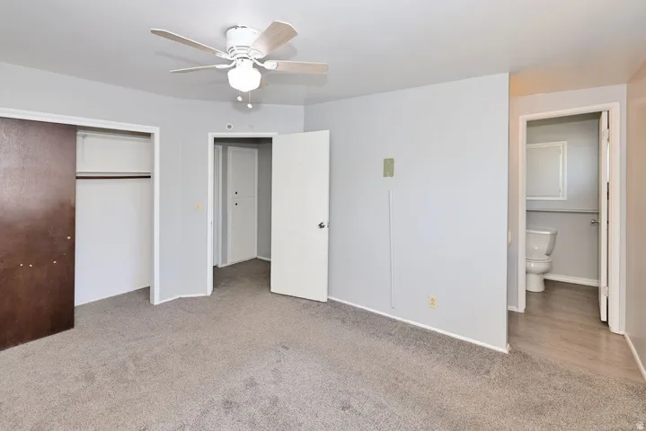 Carpeted flooring, ceiling fan with integrated lighting, and a sliding door closet with built-in shelving