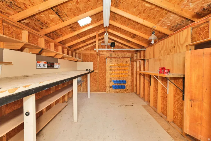 Vaulted wood-paneled ceiling with exposed beams, built-in shelving, concrete flooring, and skylight