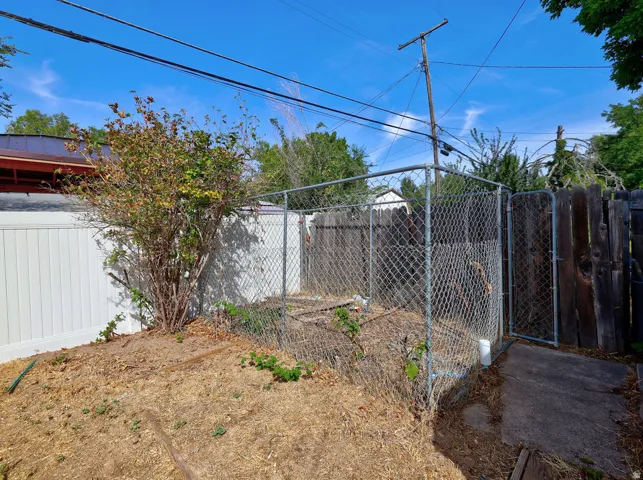 Chain link enclosure, wood privacy fence, white privacy fence, mature shrubbery, paved pathway