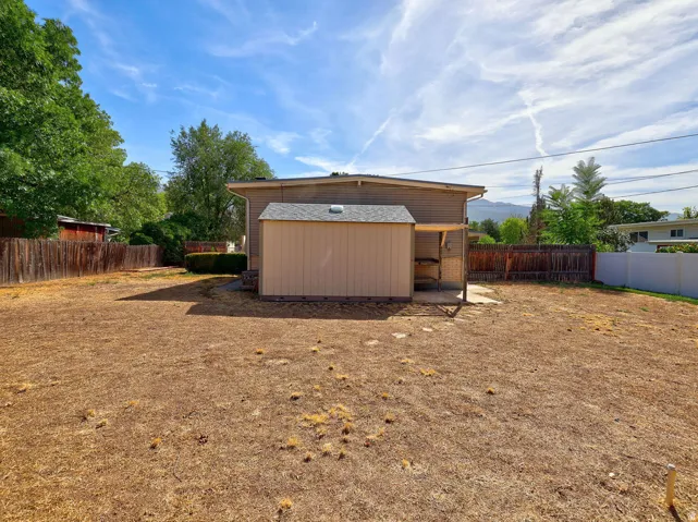 Expansive yard with a storage shed and a covered patio area
