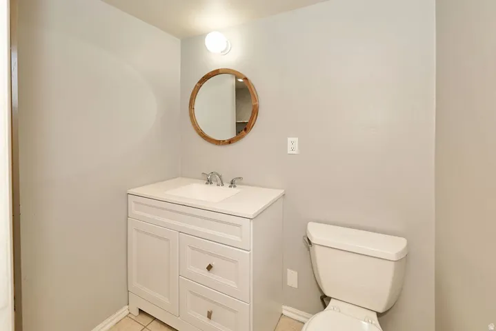 White vanity with a single basin sink, chrome faucet, and round wood-frame mirror