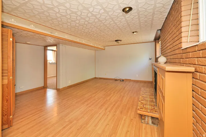 Brick accent wall with a built-in fireplace, wood-finish flooring, recessed lighting, and a textured ceiling