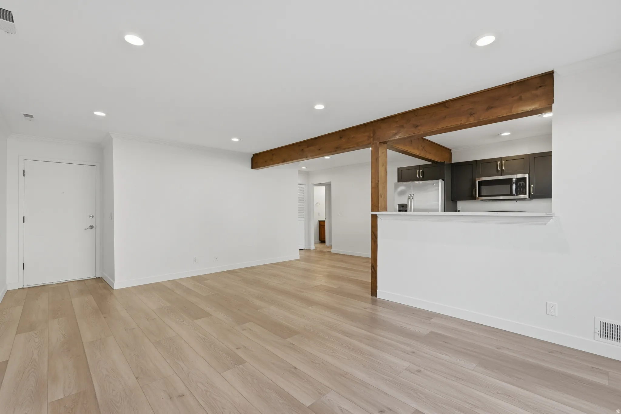 Open-concept living space featuring wood-finish flooring, recessed lighting, and exposed wood beams