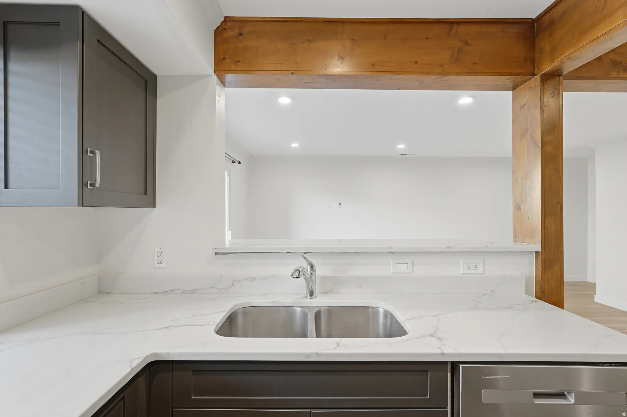 Kitchen with white countertops, a stainless steel double basin sink, and wood-finish support beams