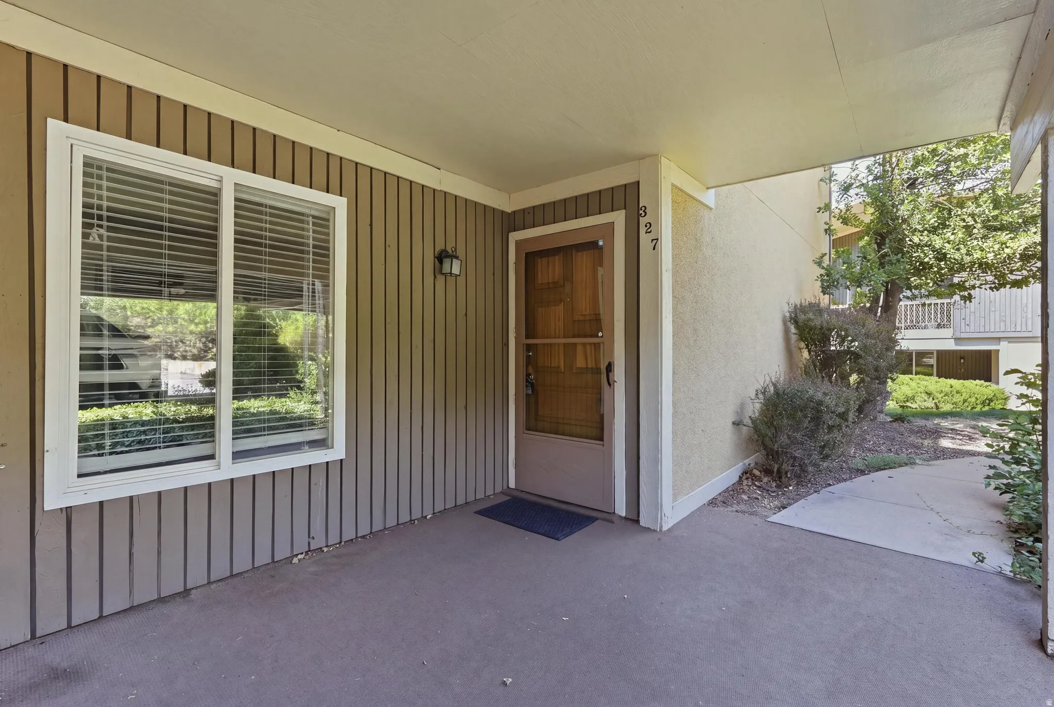 Covered entry with concrete flooring, vertical wood-panel siding, and a white-framed window