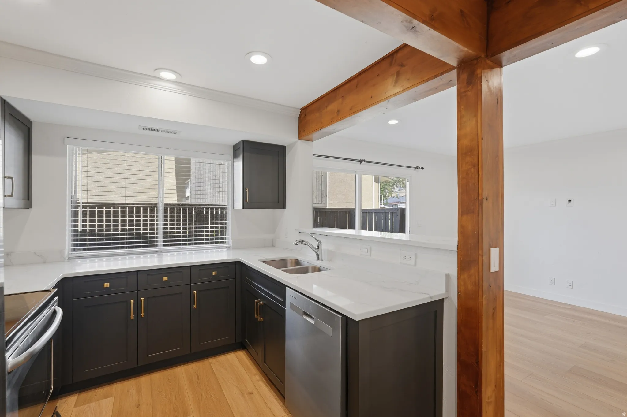 Kitchen featuring dark cabinetry, light countertops, wood-finish flooring, recessed lighting, and a stainless steel double basin sink