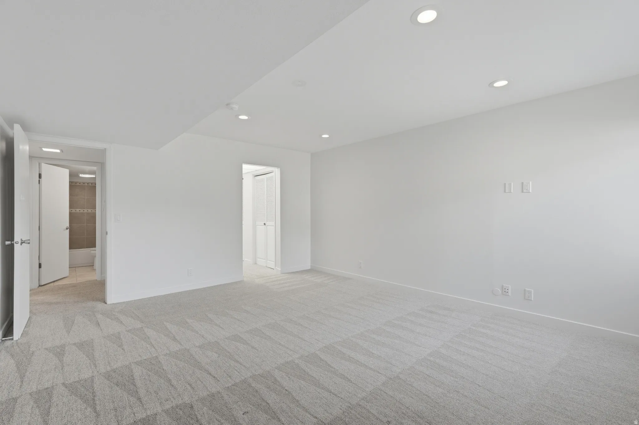 Recessed ceiling lighting, patterned carpet flooring, white painted walls, and white doors