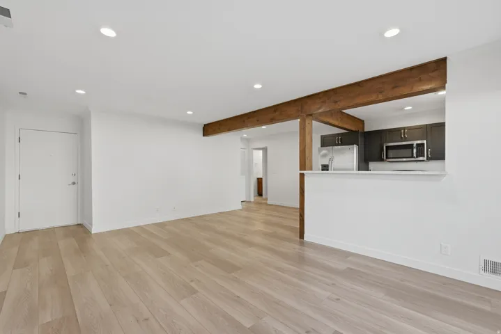 Open-concept living space featuring wood-finish flooring, recessed lighting, and exposed wood beams