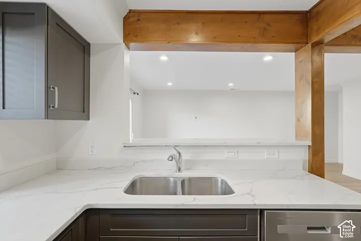 Kitchen with white countertops, a stainless steel double basin sink, and wood-finish support beams