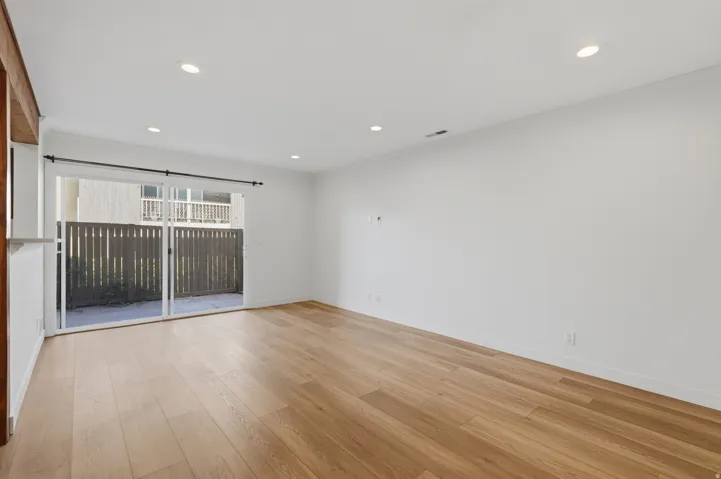 Spacious room featuring wood-finish flooring, recessed lighting, and a sliding glass door