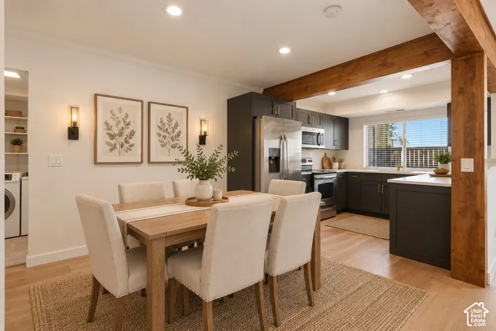 Kitchen featuring dark cabinetry, stainless steel appliances, wood-finish flooring, exposed wooden support beam, and recessed lighting