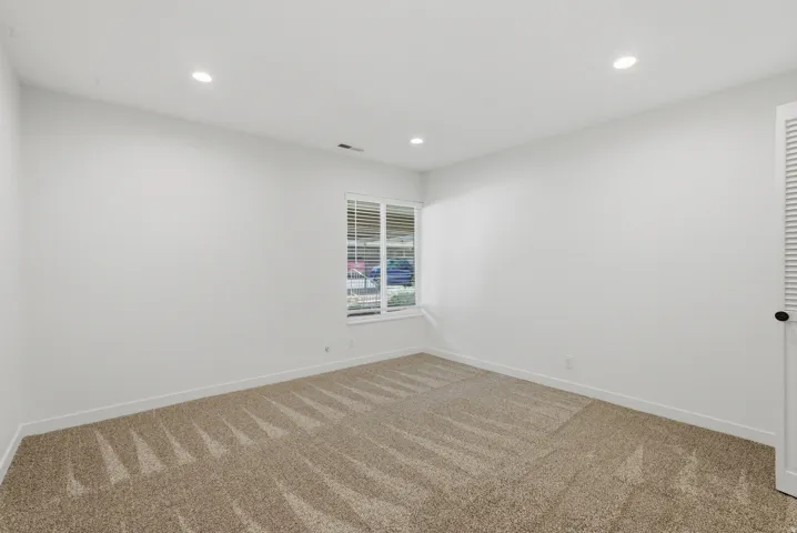 Recessed ceiling lighting, window with blinds, neutral wall paint, textured carpeting, louvered door