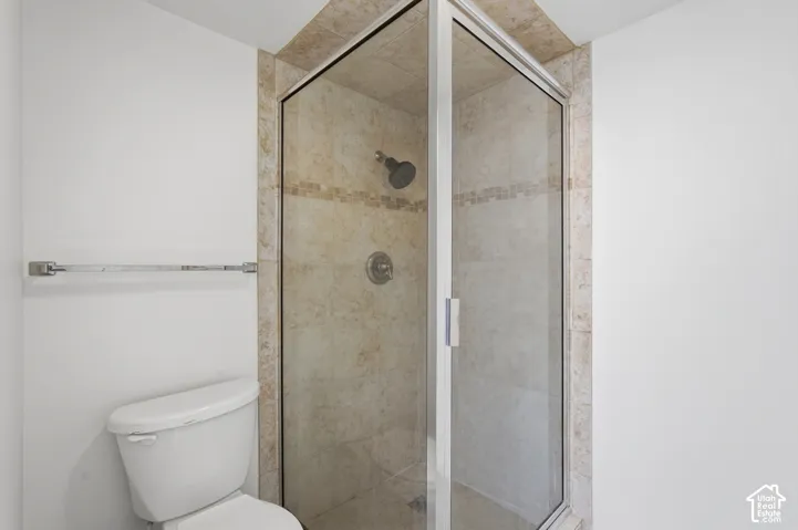 Glass-enclosed shower with tiled walls and chrome fixtures