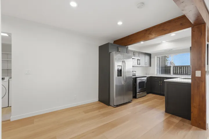 Kitchen with dark cabinetry, stainless steel appliances, light countertops, and wood-finish flooring