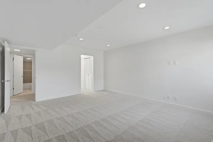 Recessed ceiling lighting, patterned carpet flooring, white painted walls, and white doors