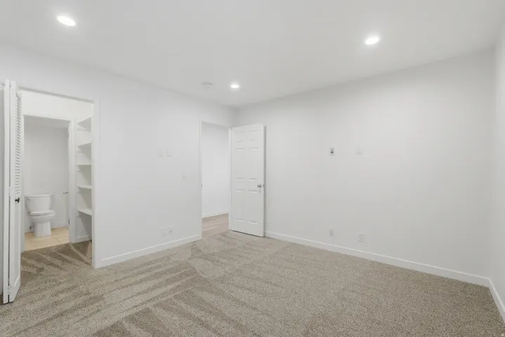 Recessed ceiling lighting, white walls, and soft gray carpet flooring