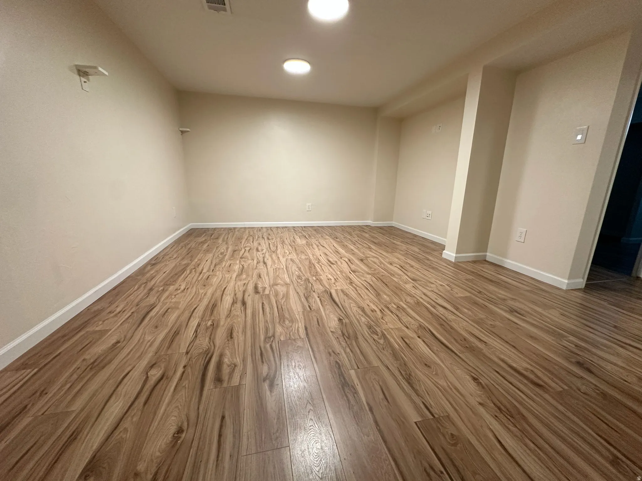 Wood-finish flooring, recessed lighting, neutral wall paint, and white trim