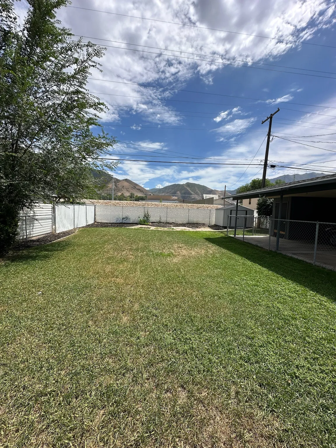 Expansive lawn area with a chain-link perimeter fence, backed by distant mountains