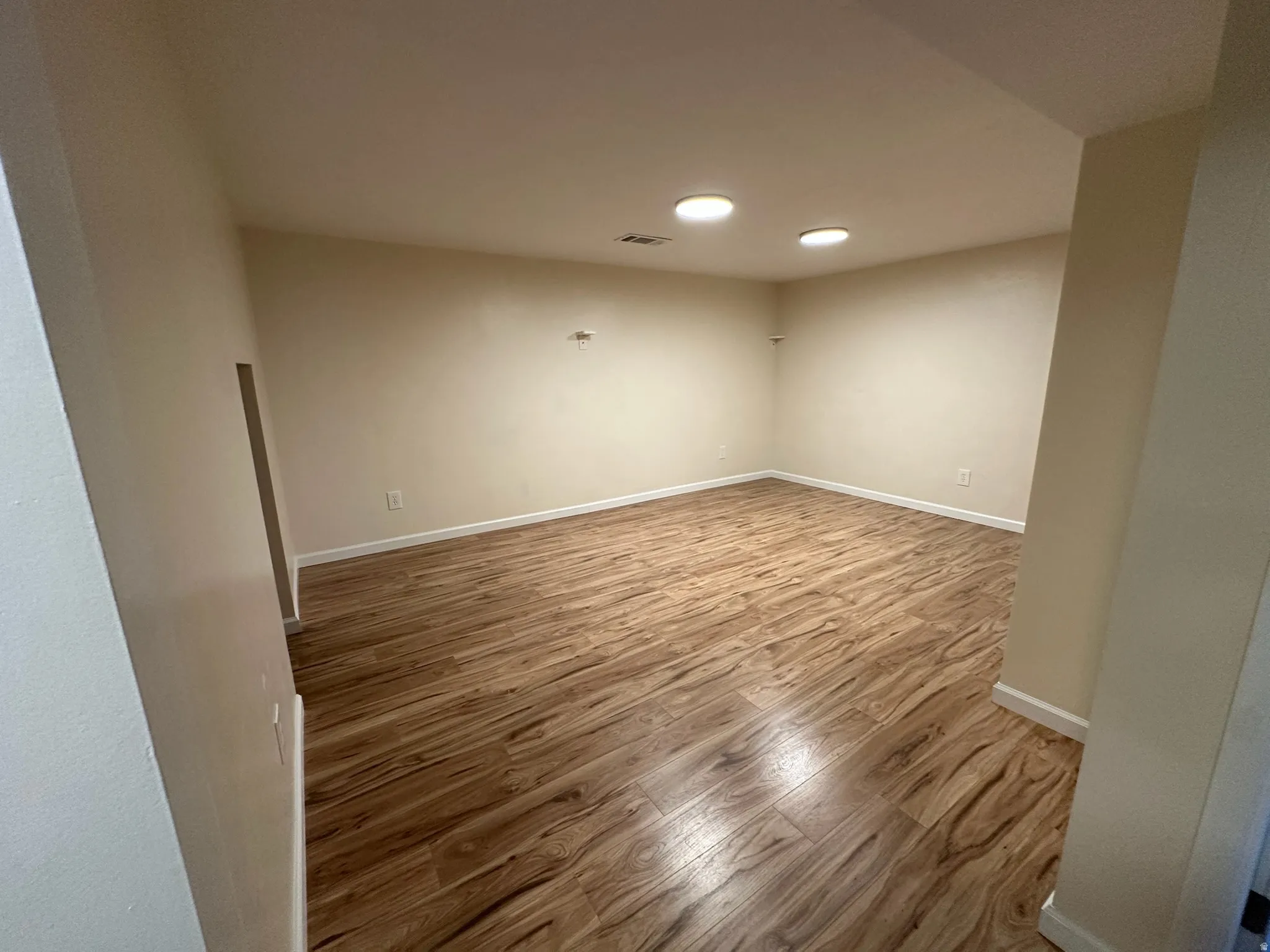 Recessed lighting, wood-finish flooring, and light-toned walls