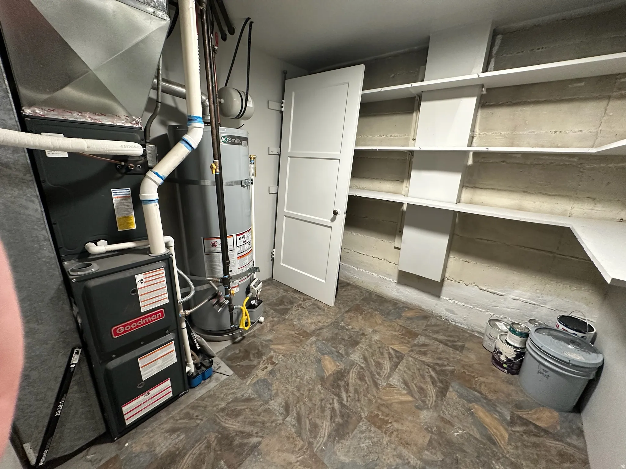 Goodman furnace, hot water heater, built-in shelving, and utility door