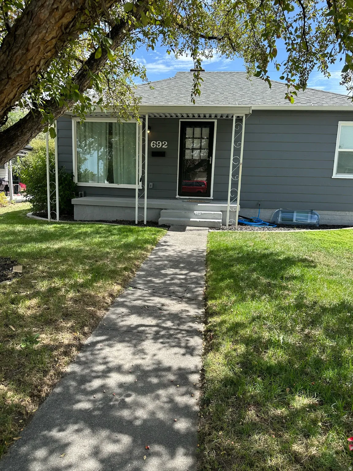 Front exterior with a covered porch, dark gray siding, a black front door with glass panels, and a concrete walkway