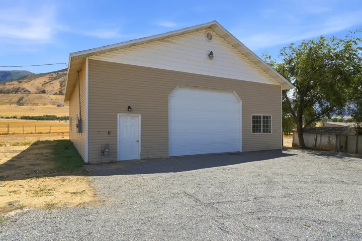 Detached auxiliary building with a large roll-up door, side entry door, and multi-pane window