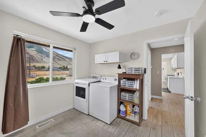 Utility room with wood-finish tile flooring, a mounted ceiling fan, and built-in white cabinetry