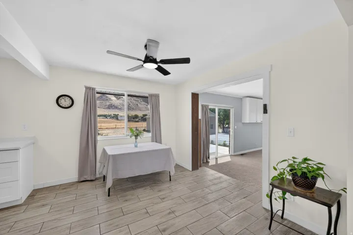 Wood-finish flooring, ceiling fan, white cabinetry, and sliding glass door
