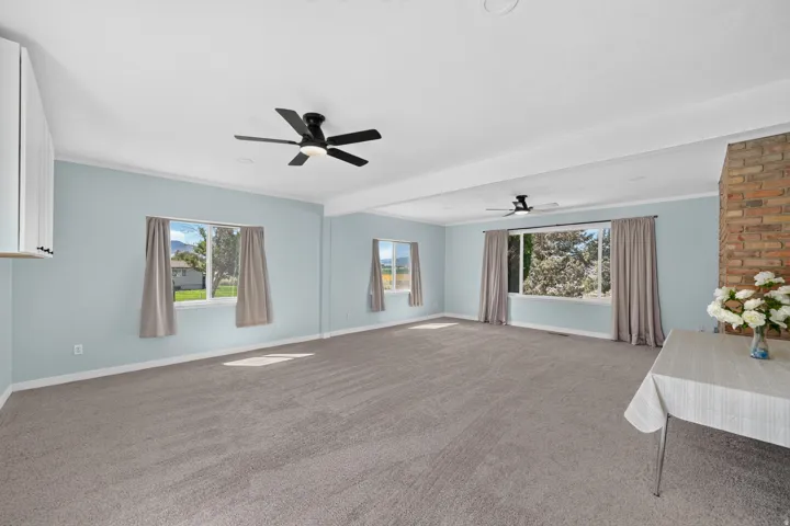 Spacious room featuring neutral carpeting, light-colored walls, and a visible brick accent wall