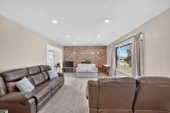 Spacious room with recessed lighting, brick-finish accent wall, and light-toned carpeting