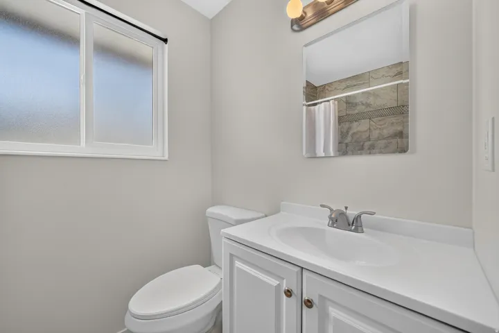 White vanity with integrated sink, chrome faucet, and bronze hardware