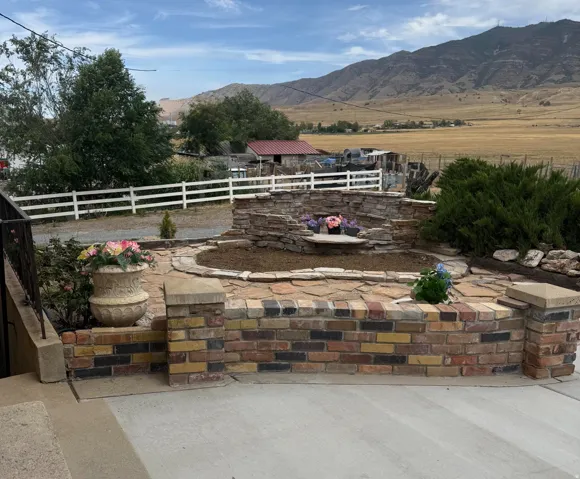 Multi-tone brick planter with stone cap, stacked stone water feature, and flagstone paving