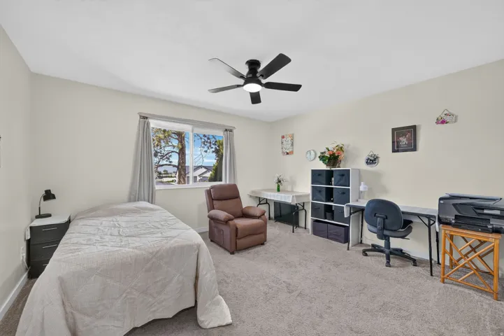 Wall-to-wall carpeting, a window providing natural light, and a ceiling fan with integrated lighting