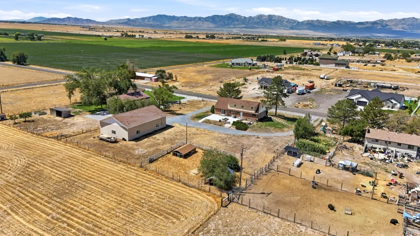 Extensive property featuring a two-story residence with an attached garage, a large detached outbuilding, fenced acreage, and surrounding agricultural land