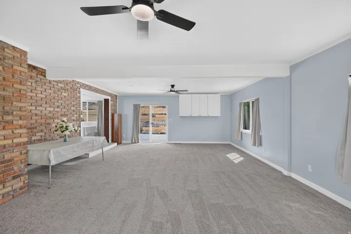 Expansive interior with light blue walls, gray carpeting, and exposed brick wall detailing