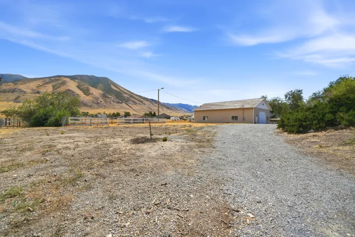 Gravel driveway leading to a detached structure with a pitched roof and garage door