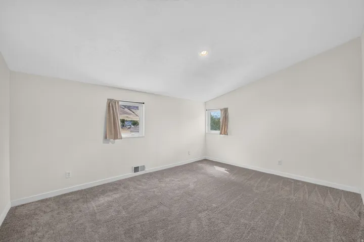 Neutral wall finishes, textured carpet flooring, and an angled ceiling