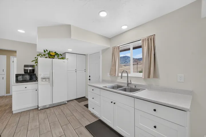 Kitchen featuring white cabinetry, light countertops, wood-look tile flooring, and a double basin sink with a gooseneck faucet