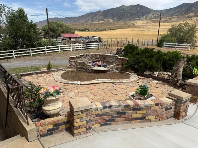 Stone patio area featuring a built-in stone water feature and a retaining wall with multicolored brick