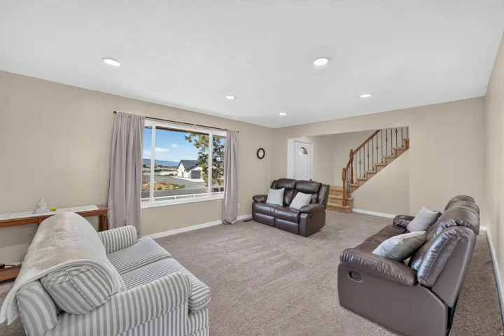 Recessed lighting, wood-finish staircase with wrought iron spindles, neutral paint palette, and a large picture window