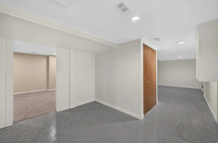 Recessed lighting illuminates the space, featuring a wood-finish bi-fold closet door and durable epoxy flooring